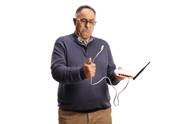 Older man holding a wifi router and cord looking puzzled